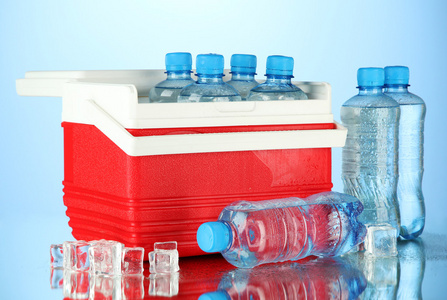 旅行冰箱用瓶的水和冰的多维数据集，在蓝色背景