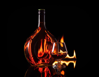 瓶 glass 的科涅克白兰地在黑色背景上的圣火