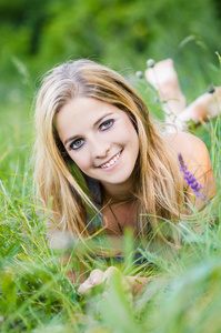 美丽的年轻长发女子躺在绿色的原野