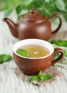 茶壶与杯新鲜薄荷花在木桌上的花草茶