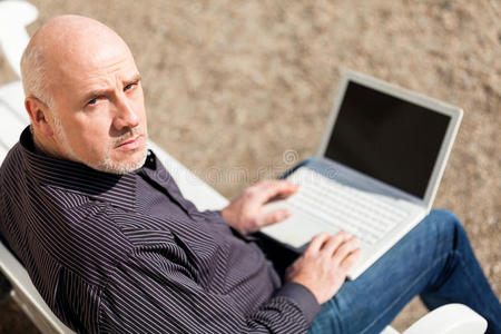 坐在长凳上用笔记本电脑的人