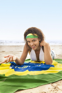 海滩上年轻迷人的女孩手举巴西国旗