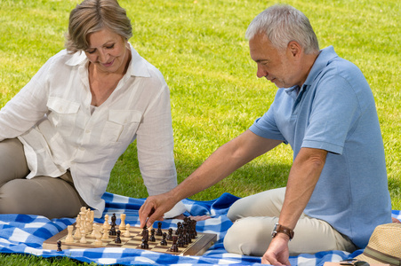 在公园里的下棋的退休高级夫妇