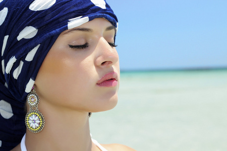 蓝披肩在海滩上美丽的女人。阿拉伯风格