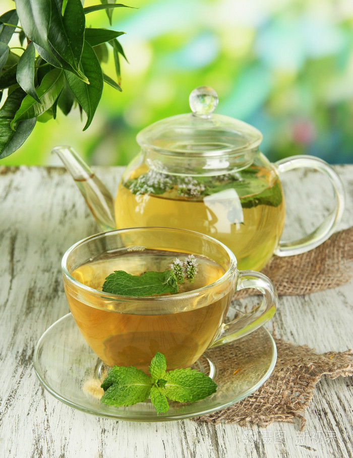 茶壶与杯新鲜薄荷花在木桌上的花草茶