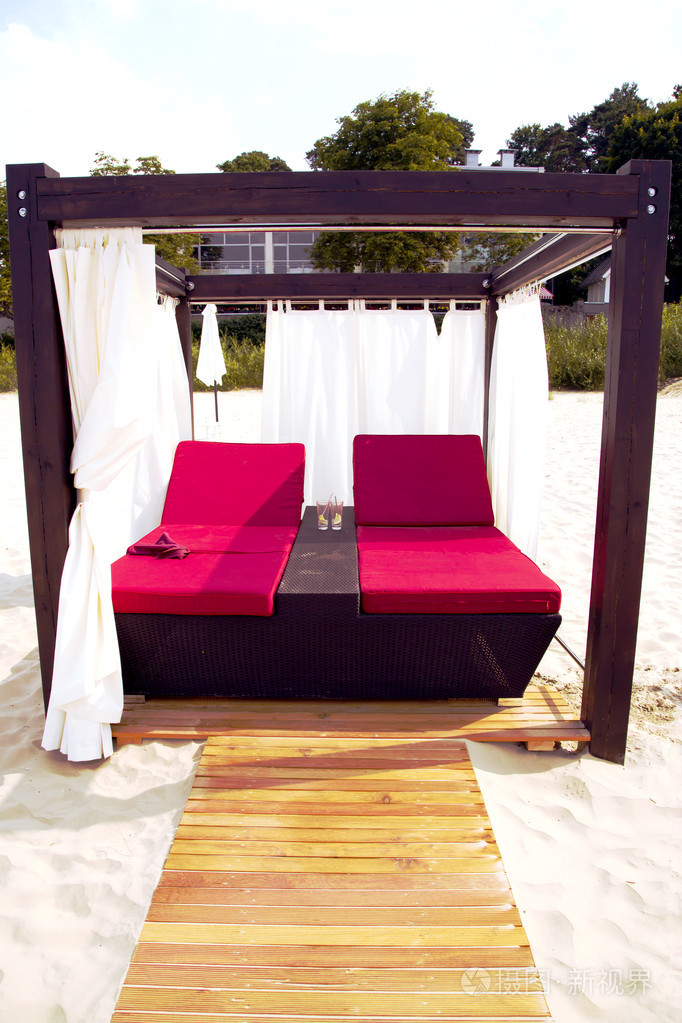 在一个大帐篷在沙滩上的两个日光浴床