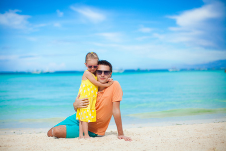 年轻的父亲和他可爱的小女儿在海滩得开心
