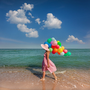 与在沙滩上散步的年轻女子彩色气球放松