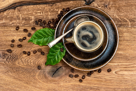 杯黑咖啡，豆和木桌上的叶子 抽象的背景