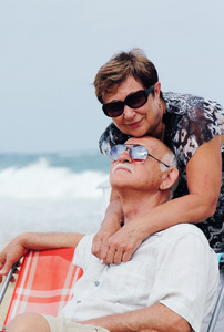 快乐在一起坐在海滩上的高级夫妇的肖像