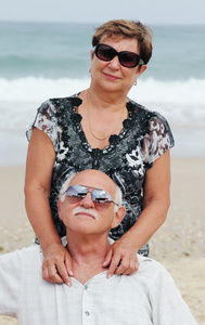 快乐在一起坐在海滩上的高级夫妇的肖像