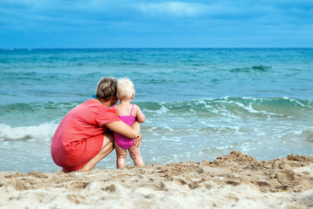 幸福的母亲和他的小女儿在海滩上