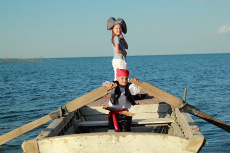 微笑开朗的男孩和女孩在海盗玩穿着西装和帽子