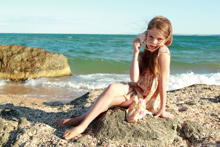 可爱的女孩与一个美丽的笑容，打赤脚在海滩上水