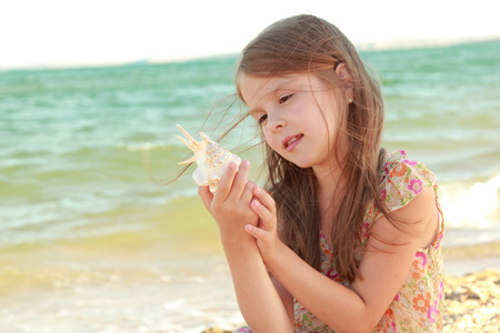 可爱的小女孩用微笑和持有贝壳梦的肖像