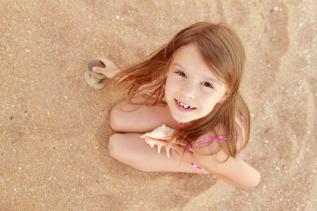 在泳装举行美丽的贝壳微笑着漂亮的小女孩的肖像