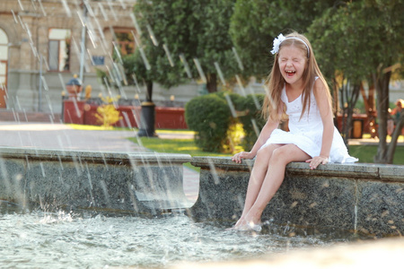 快乐与美丽的头发的年轻女孩才子英尺的喷泉在炎热的夏天一天