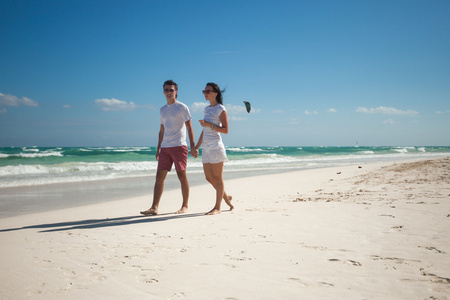 年轻的夫妇在异国风情的海滩上走在阳光灿烂的日子