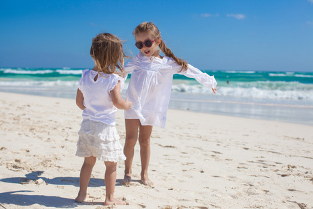 在穿白衣服的两个小姐妹在热带墨西哥海滩上玩得开心