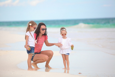 年轻的母亲和她可爱的女儿在热带海滩享受暑假