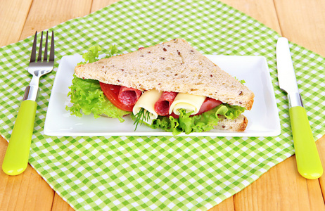 好吃的三明治与萨拉米香肠和蔬菜上白板，木制背景上