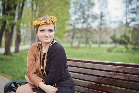 女孩坐着黄色的花朵在她头上的花环