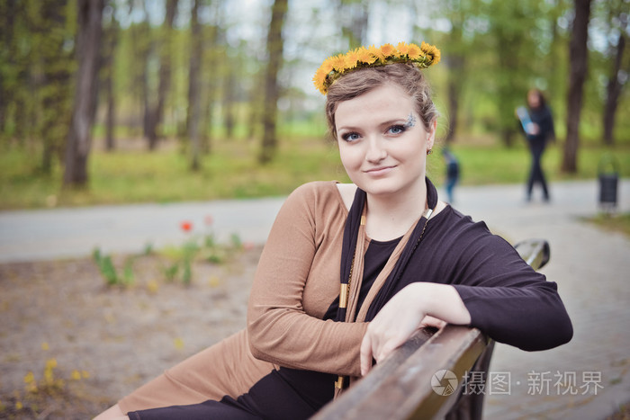 女孩坐着黄色的花朵在她头上的花环