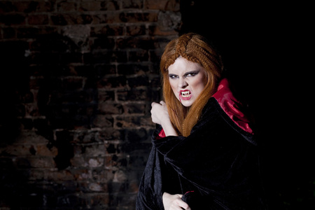 红红的嘴唇被吸血鬼咬伤性感的年轻女子在户外冬季背景喝受害者的血的