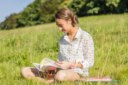美丽年轻的学生读一书在公园