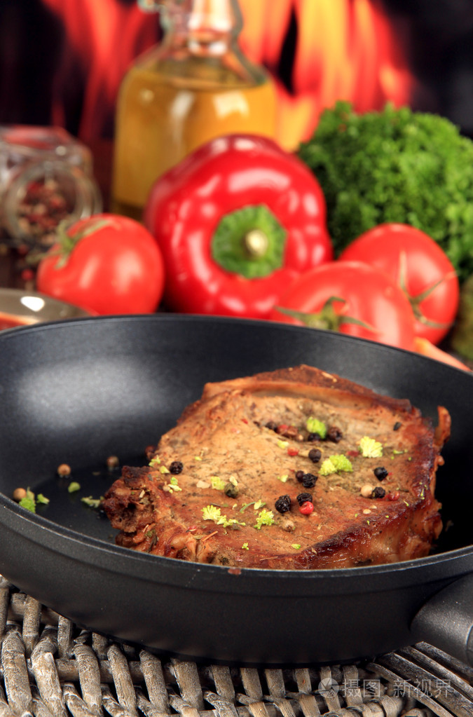一块煎肉火背景上的木桌上平底锅上