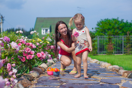 年轻的母亲和她可爱的女儿在花园的夏季时间玩得开心