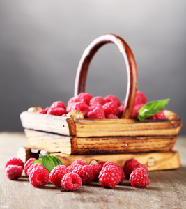 成熟甜树莓在木桌上，灰色的背景上篮