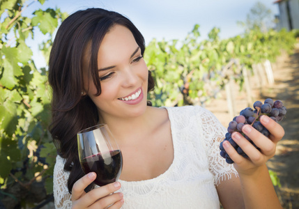 年轻成人女人享受一杯酒的葡萄园