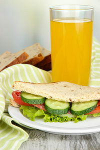 作文与果汁和美味三明治与萨拉米香肠和蔬菜上彩色餐巾，木桌上，在明亮的背景上