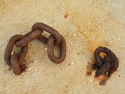 极端腐蚀的固定在混凝土块中的链链接。耐盐雾腐蚀的铁链在海港口