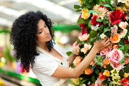 美丽女性花店接触一些在温室中的花朵