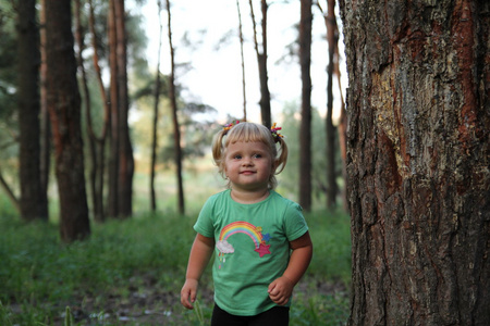 可爱的小金发女孩附近一棵树