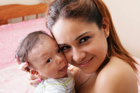 西班牙裔美国人快乐年轻的母亲抱着一个婴儿的肖像