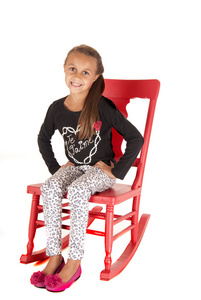 年轻的黑发女孩坐在粉红色的摇椅上