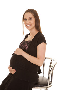 怀孕的女人的衣服坐在寻找微笑