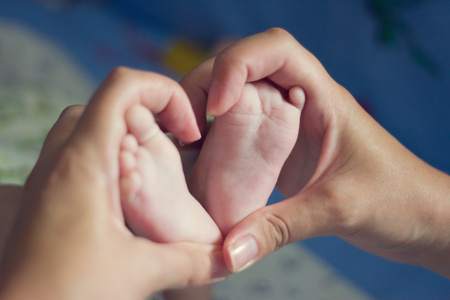 小小的婴儿脚用妈妈的手