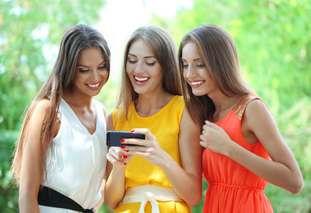 三个美丽的年轻女子，与智能手机中夏公园