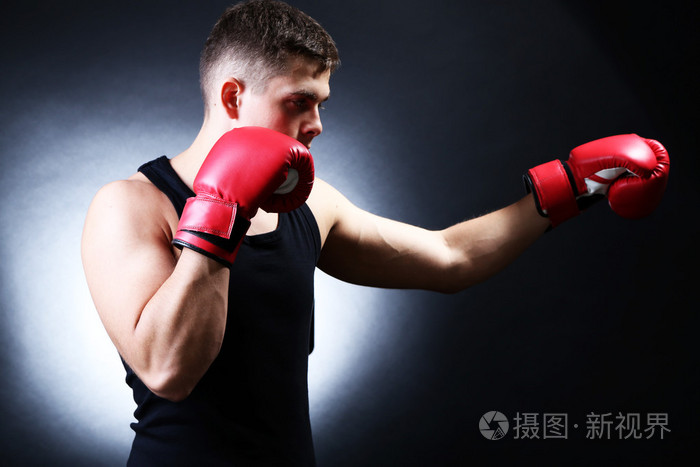 英俊年轻的肌肉拳击手在深色背景上