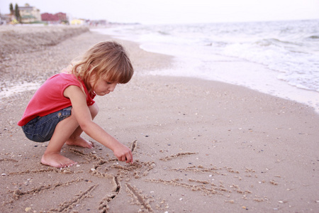 小女孩在沙画在沙滩上