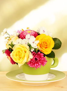 束美丽的鲜艳的花朵颜色杯里木桌上，在明亮的背景上