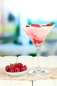树莓牛奶甜点在鸡尾酒杯，在明亮的背景上