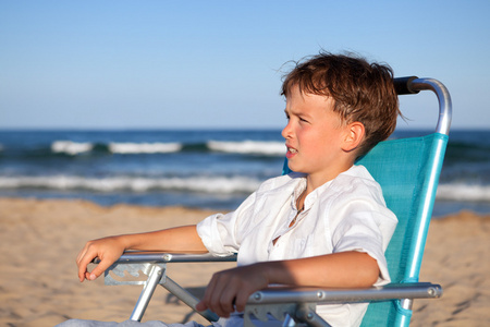 周到的男孩坐在椅子上海滩上