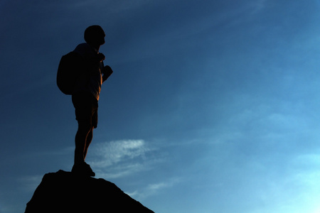 站在山顶上的寂寞男名徒步旅行者照片