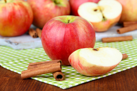 成熟的苹果与肉桂棍棒彩色木制背景上