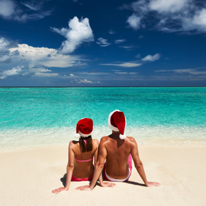 在圣诞老人的帽子在马尔代夫的海滩上的情侣